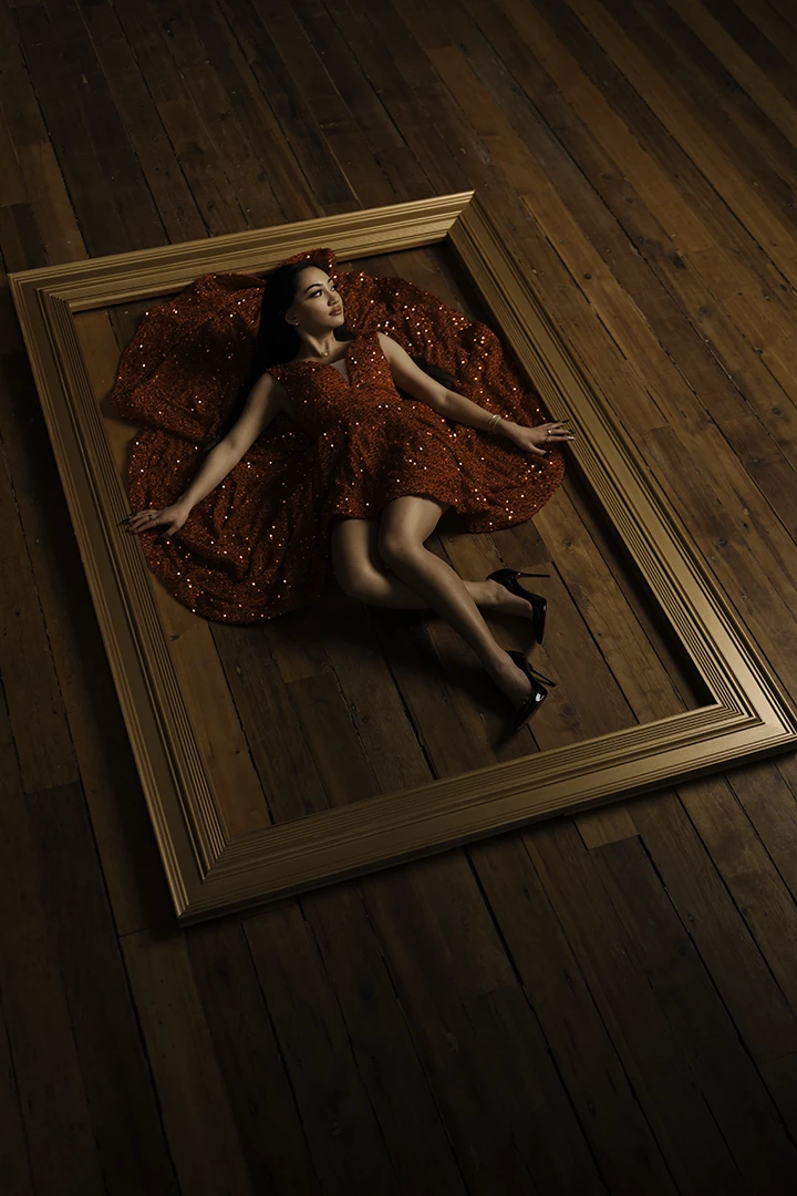 young woman laying in large wooden frame - graduation portraits