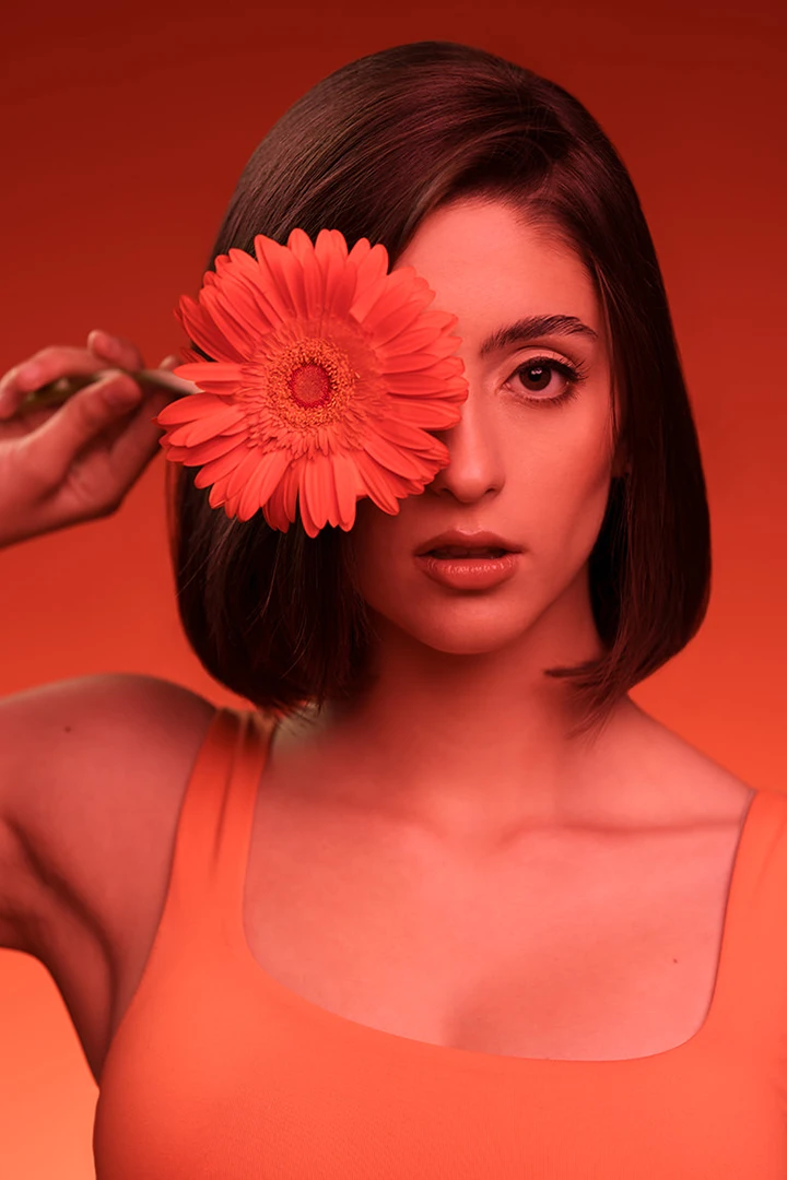 young woman holding flower in front of eye for family portrait