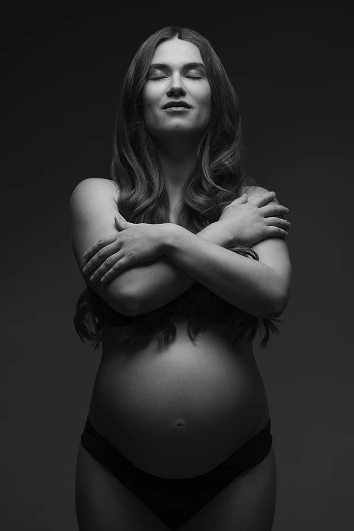 woman posing for maternity portrait in black and white at photo studio